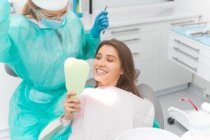 Smiling woman having professional teeth whitening treatment by hygienist in dental office.